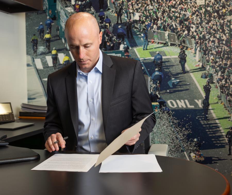 Bryce Johnston reviewing paperwork at a desk.