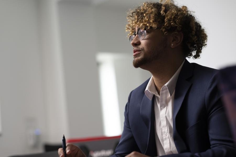 Person in business attire appears to be taking notes in a room with white walls.