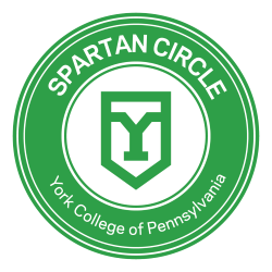 Spartan Circle logo: Green circle with graphic of York College "Y" in the middle. Text around the outside reading "Spartan Circle. York College of Pennsylvania."