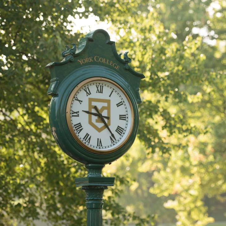 A green standing clock with gold writing that reads "York College"
