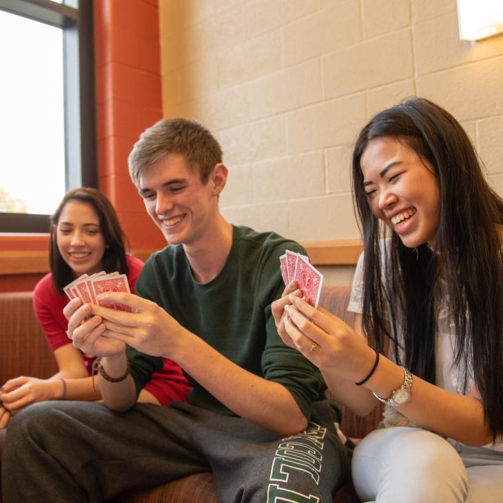 Four students play cards together in a campus residence hall