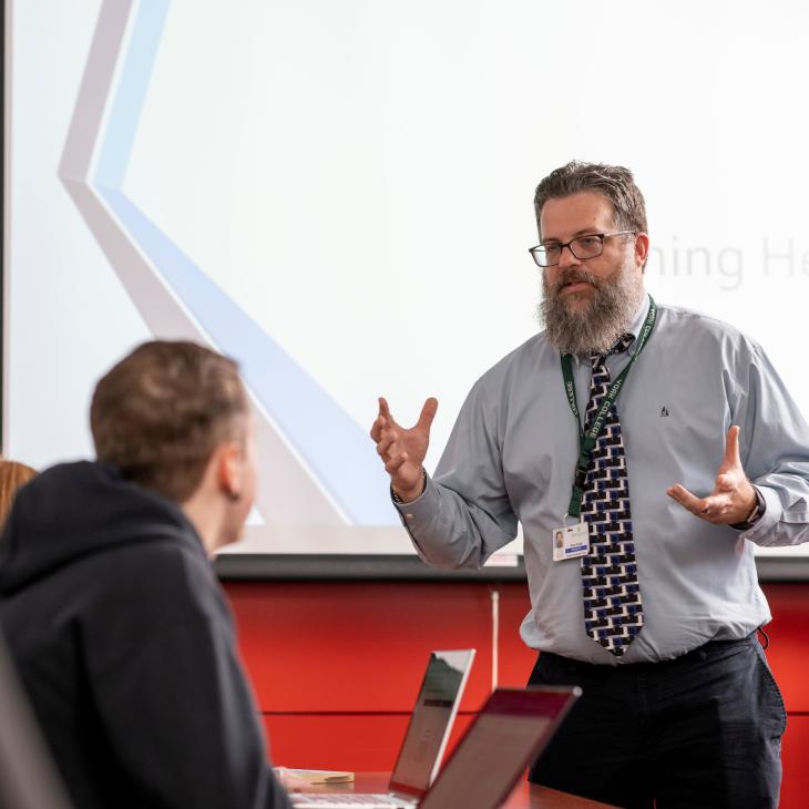 A professor standing in front of the classroom teaching.
