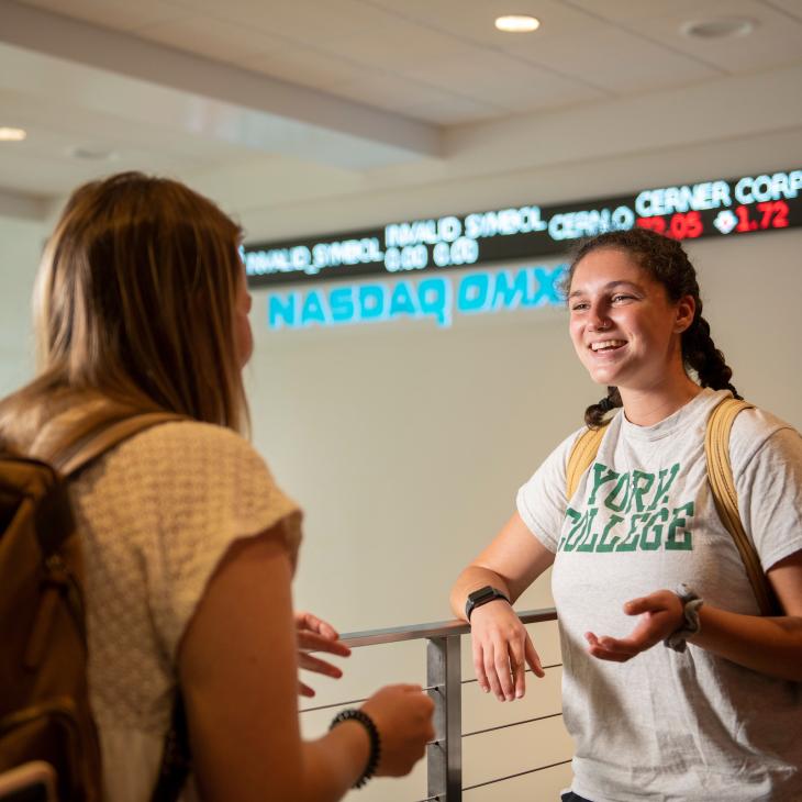 Two students chatting outside of the NASDAQ Training lab