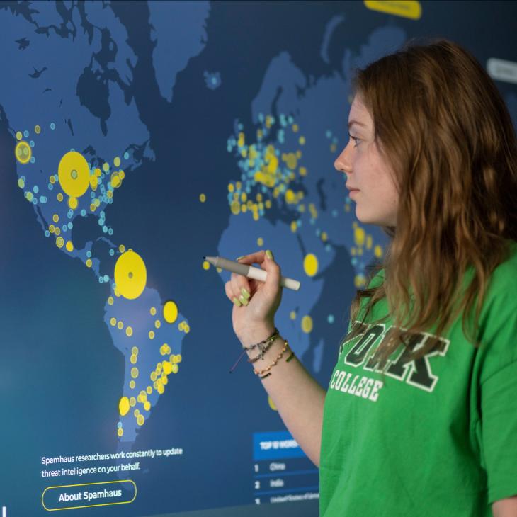 A student using the interactive board to label cybersecurity threats around the world.