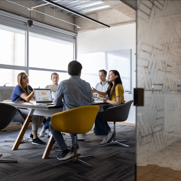 Professionals sit around a conference room table in a chic office space.
