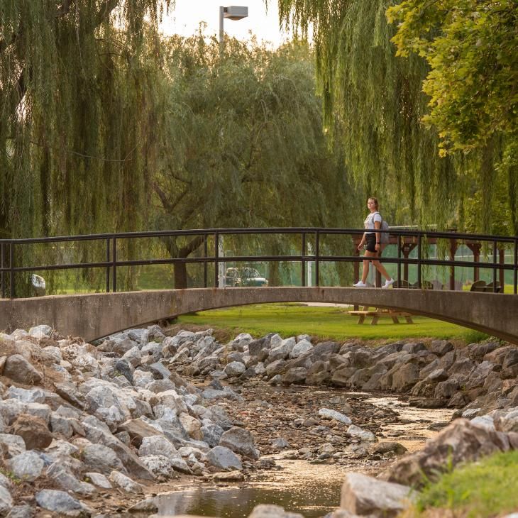 A woman walks across a bridge over the Tyler Run Creek