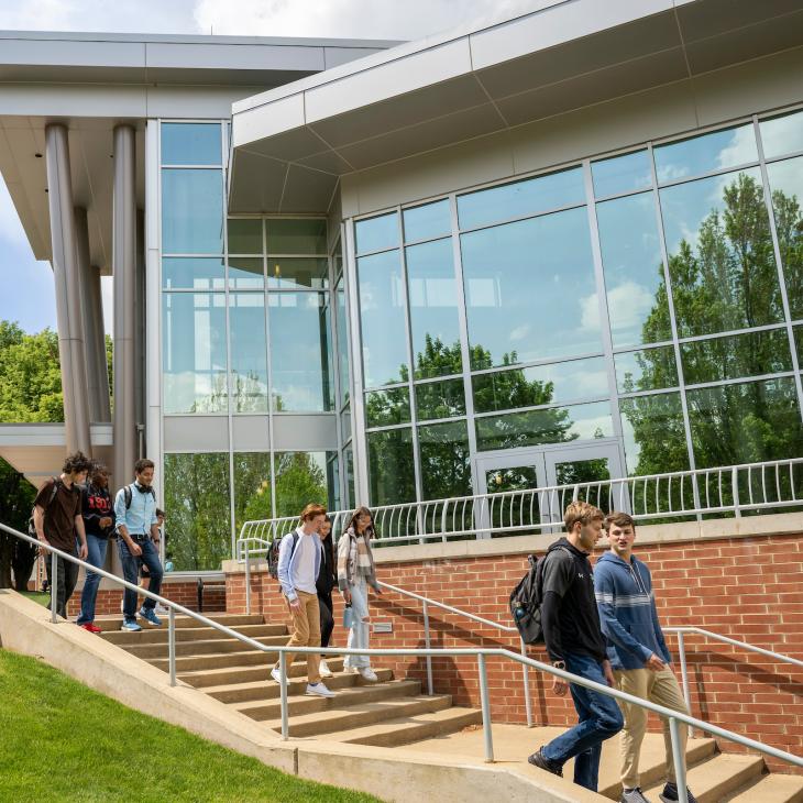 A group of several students walk down a long set of outdoor steps outside the Performing Arts Center.