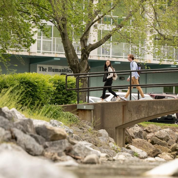Two students walk across the foot bridge over Tyler Run Creek on campus.