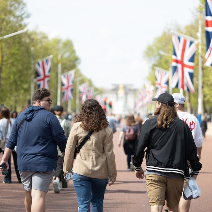 A group of students walk down a London street. Union Jack flags line the walkway.