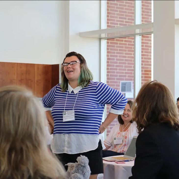 An attendee standing up in a crowd giving a speech.