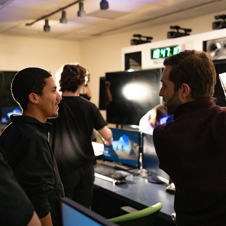 A film student learning from a professor in the film studio.