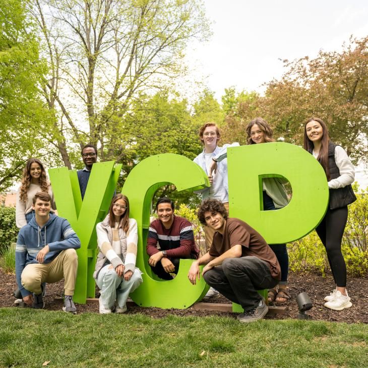 A group of students posing for a photo at the YCP letters on main campus.