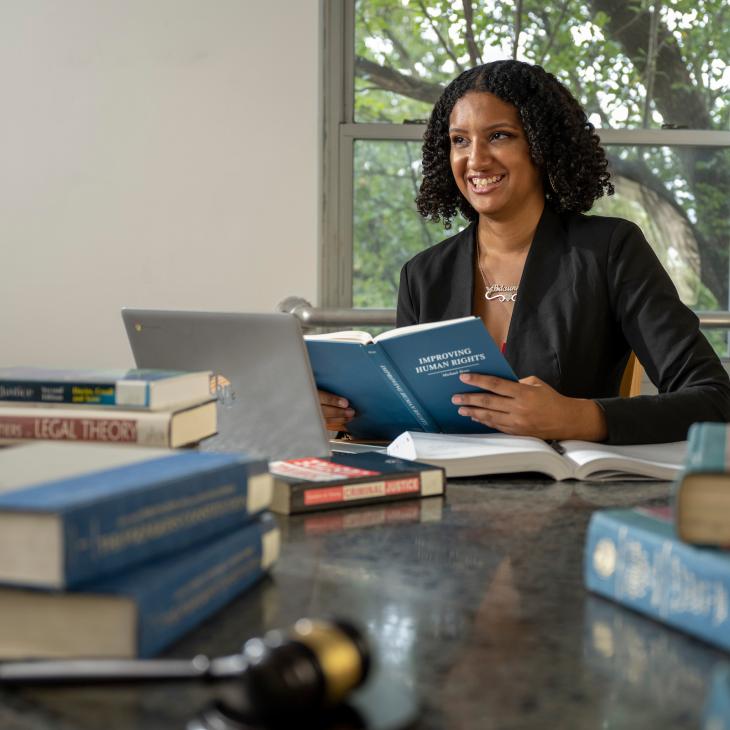 Briaunna Embrey-Bank, Criminal Justice major, sitting at a desk filled with law books.