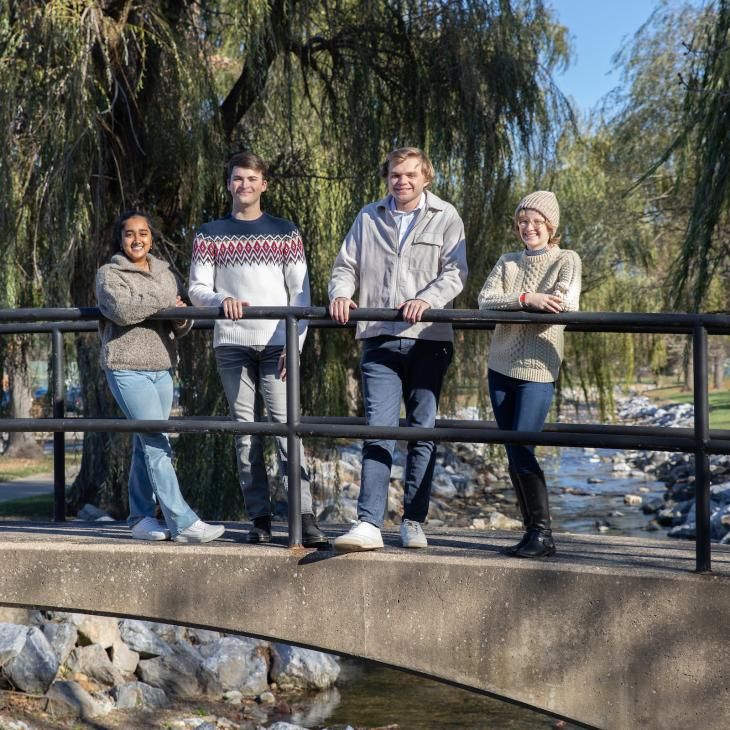 Four students gather on a footbridge over the Tyler Run Creek.