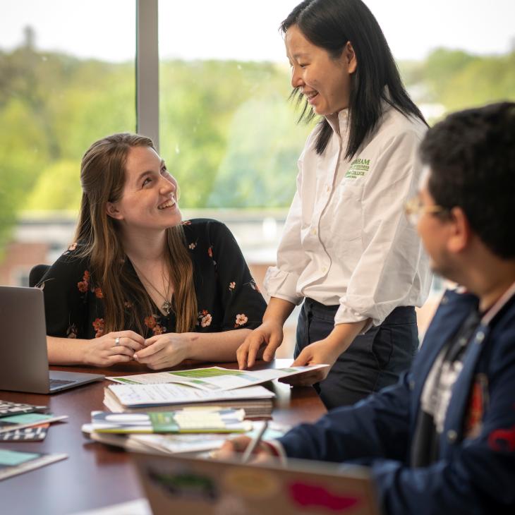 Faculty member teaching students with laptops.