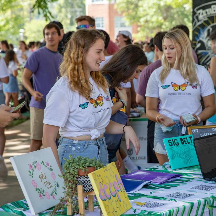 Students work at an activity fair table showcasing the work of a Greek Life organization.