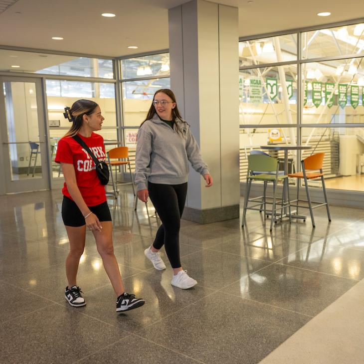 two students talking and walking into Grumbacher Sport and Fitness Center
