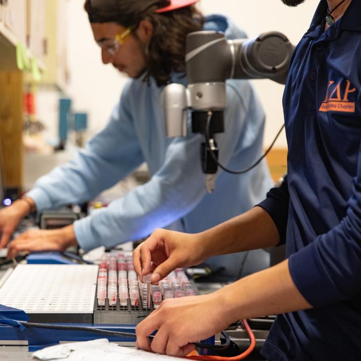 Students work at computer equipment in a lab.
