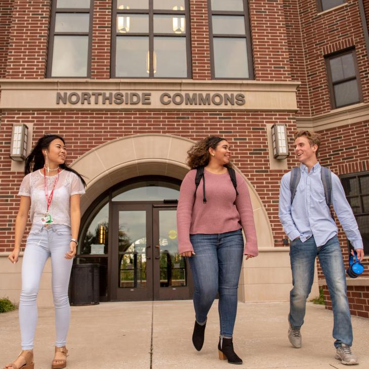three students smiling and walking in front of Northside commons