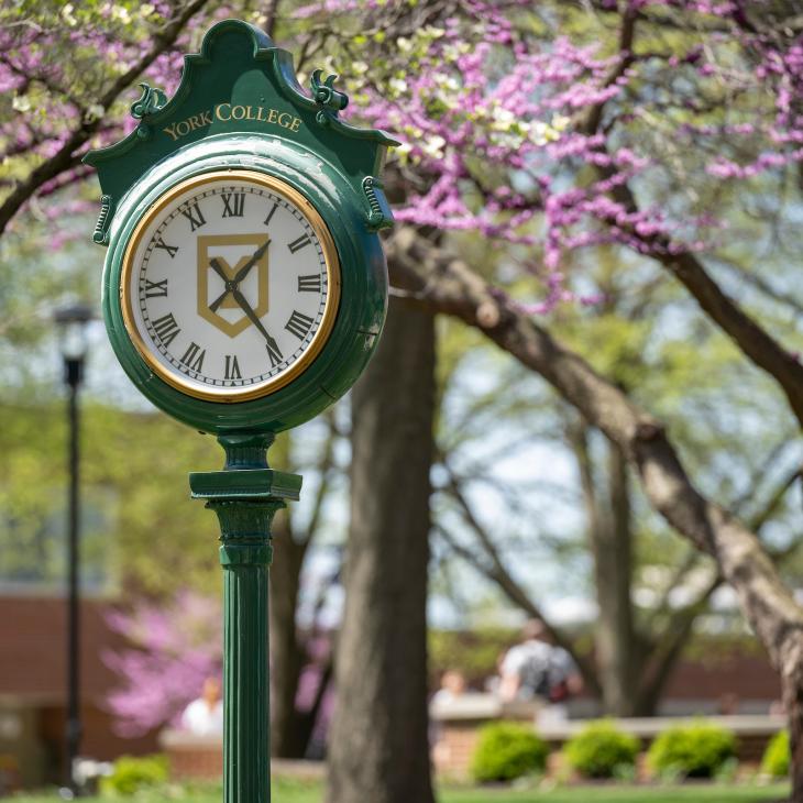 The iconic YCP clock with spring foliage in the background.