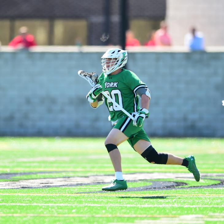 A student athlete competes on field during a lacrosse game.