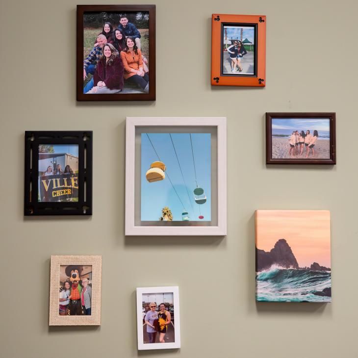 Eight photos hung up on a tan wall.