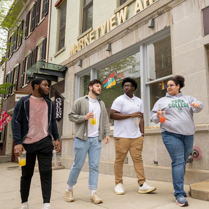A group of four students walk past Marketview Arts in Downtown York.