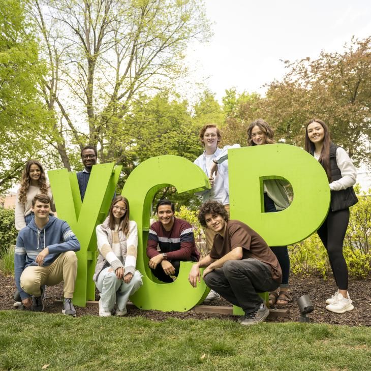 A group of students posing with the green YCP letters.