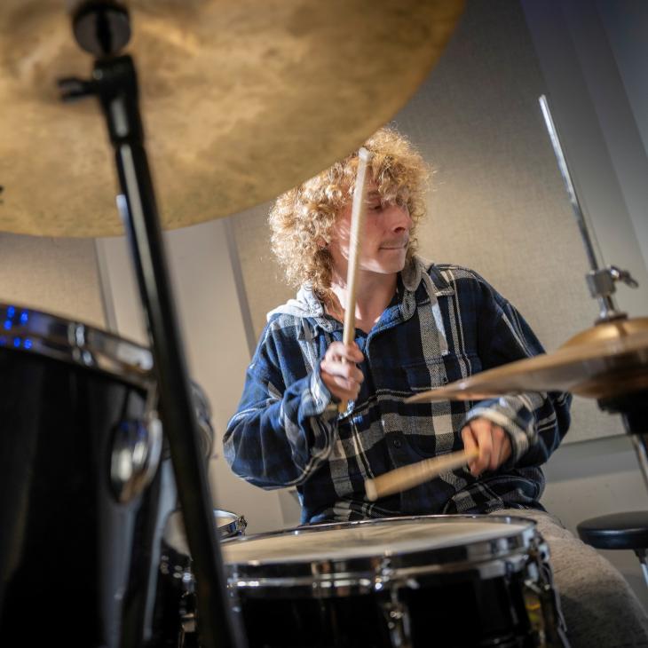 A student in the York College Rock Band plays the drums.