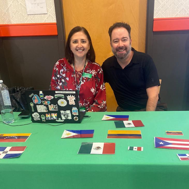 Inez Ramirez and Alex Hernández-Siegel of the Student Diversity and Inclusion office sit at a table with a display of miniature flags from Spanish-speaking countries.