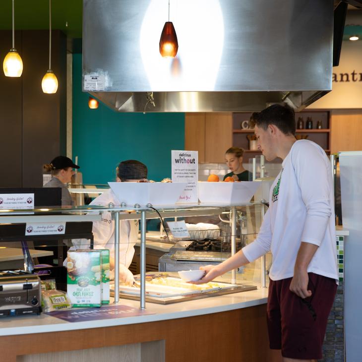 A student takes a plate at the Delicious Without dining station in Johnson Dining Hall.