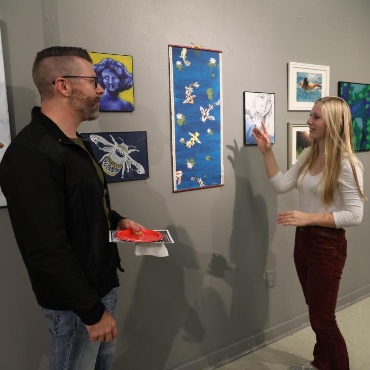 Student showing their artwork to community members during the Art Walk.