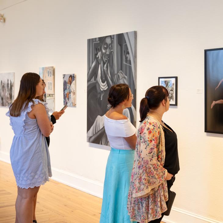 Members of the York community viewing artwork displayed on white walls in Gallery Hall.