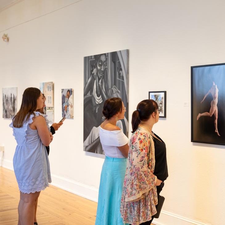 Members of the York community viewing artwork displayed on white walls in Gallery Hall.