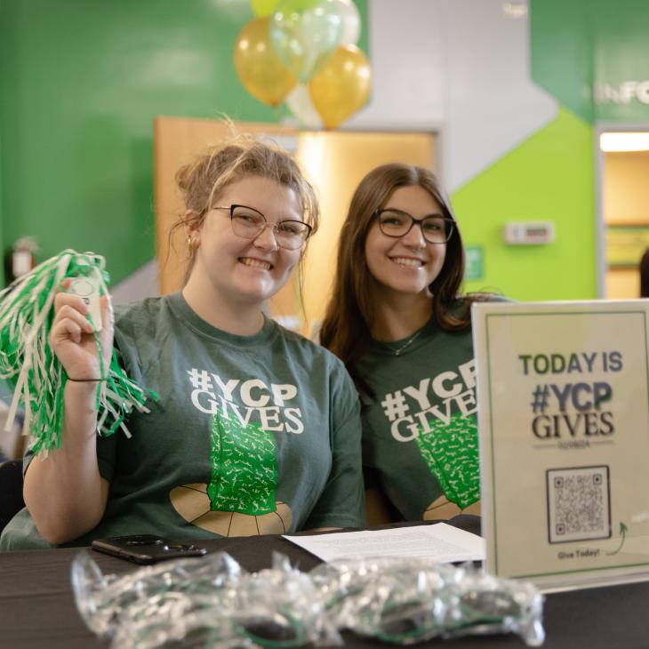 Two students wearing #YCPGives shirts in the YCP student union lobby.