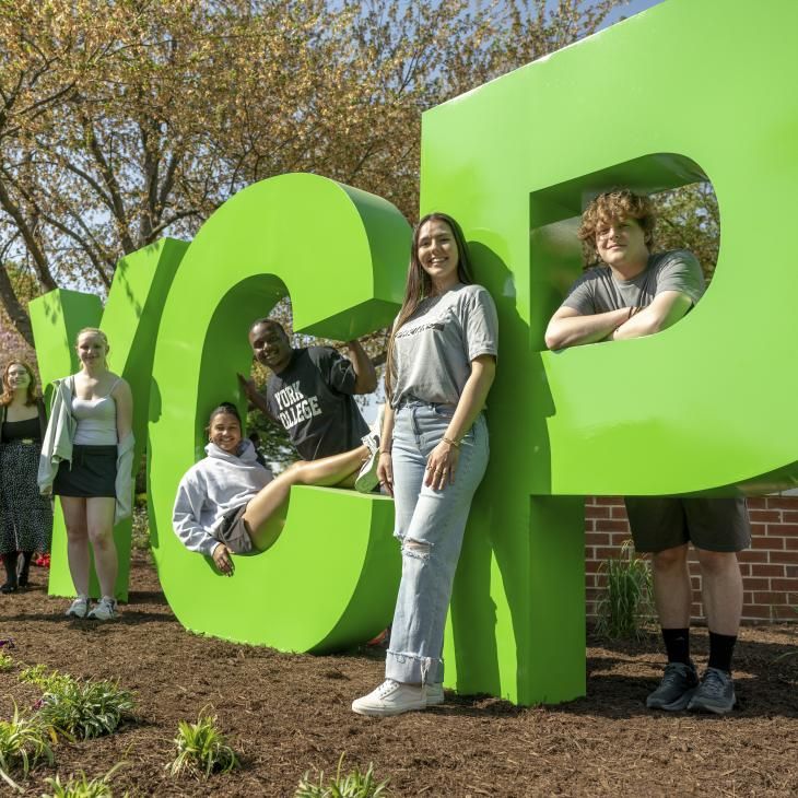 A group of students posing for a photo at the YCP letters on main campus.