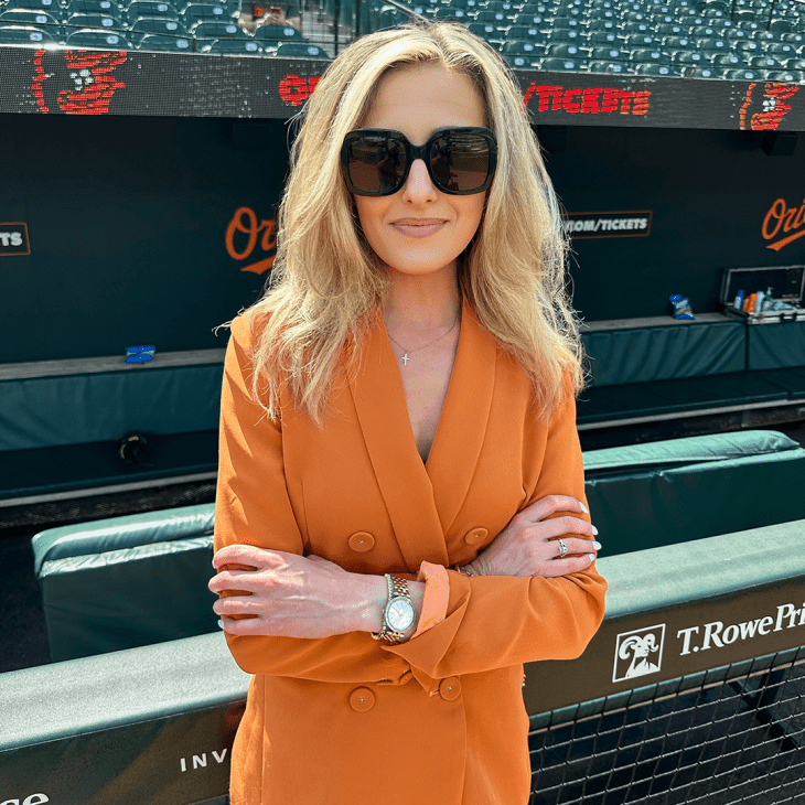Person in an orange jacket and sunglasses standing in the Baltimore Orioles stadium.