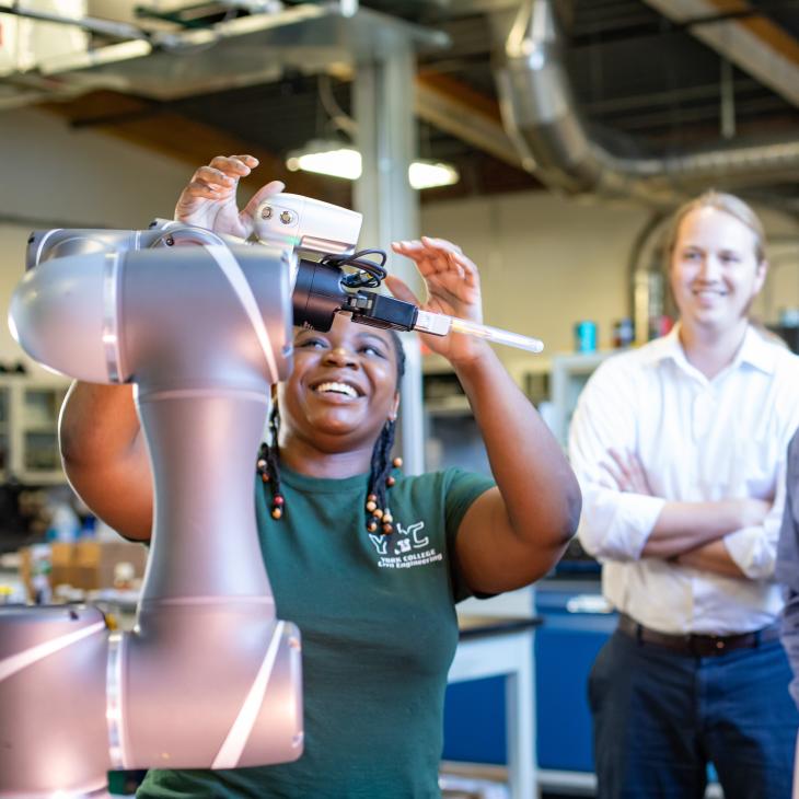 A woman demonstrates a robotic lab as three men look on