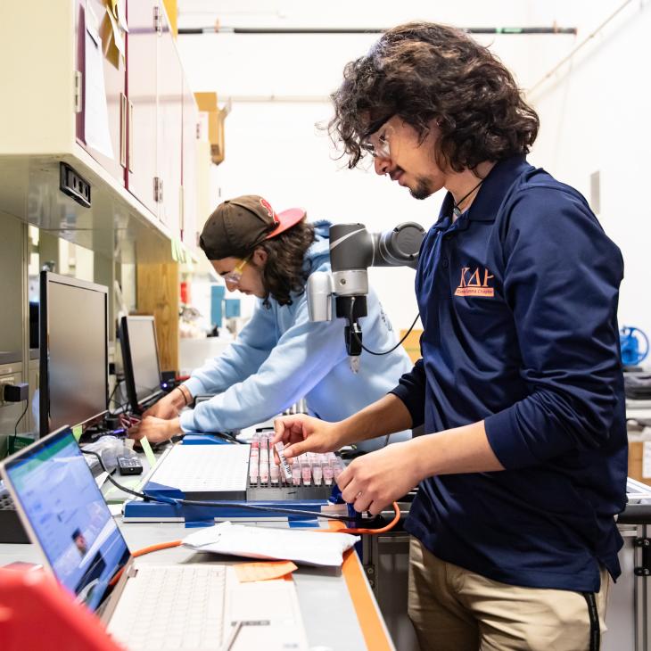 Two students work on computers in a lab setting
