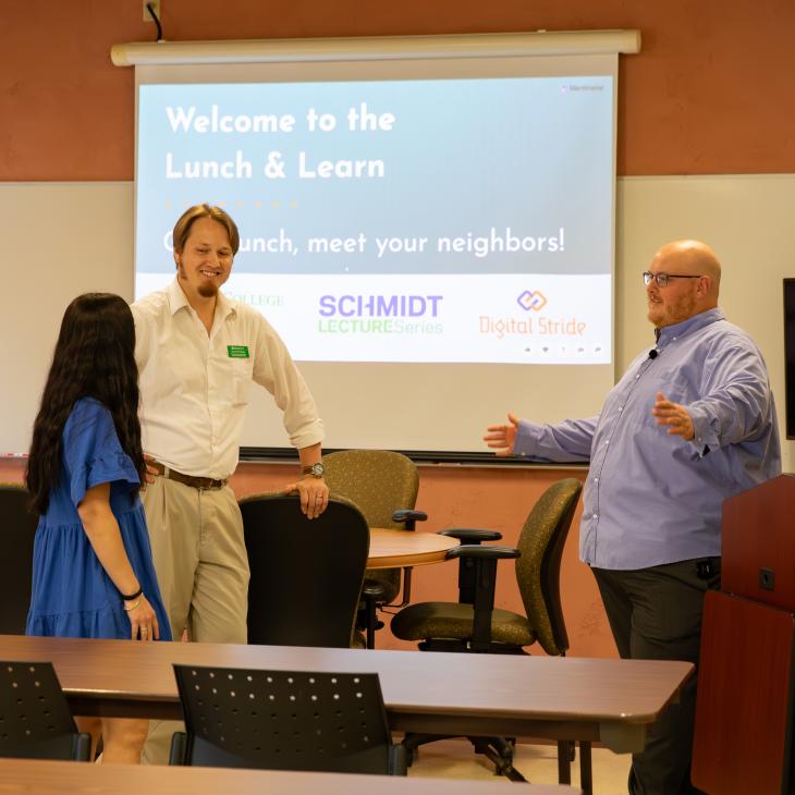 Oscar Winters talks with a woman and the speaker of a Schmidt Lecture Series