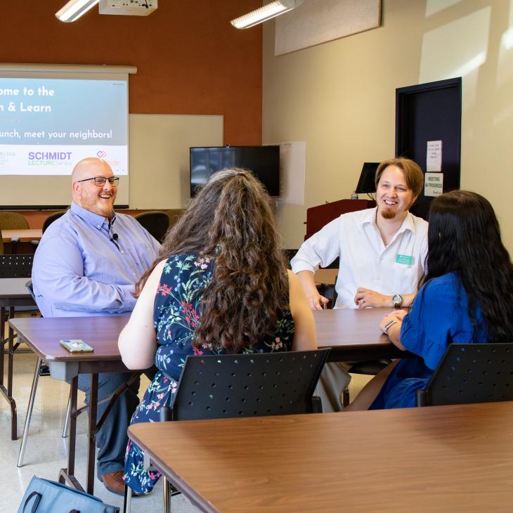 Two men and two women sit at a table talking in the JD Brown Center