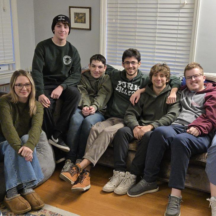 8 students sitting on the couch smiling. 