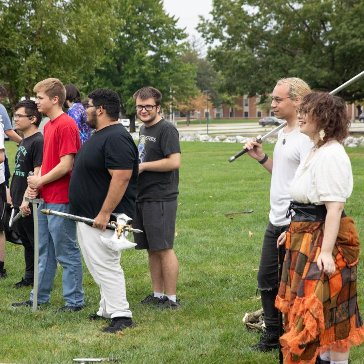 A group of students, some in costume, standing in a grassy field.