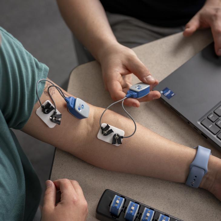 An arm with electrodes connected to a device with a computer nearby.