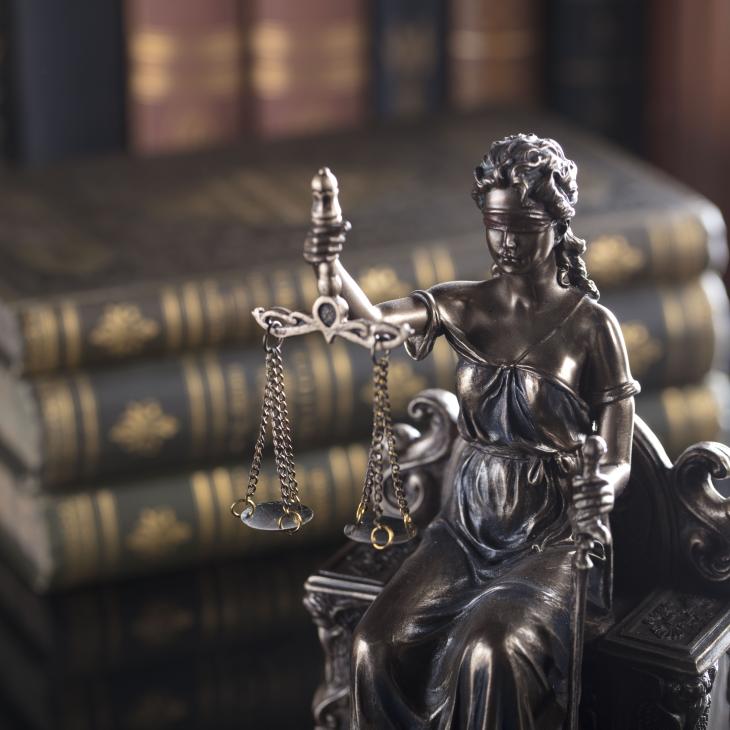 Justice statue in front of a stack of books.