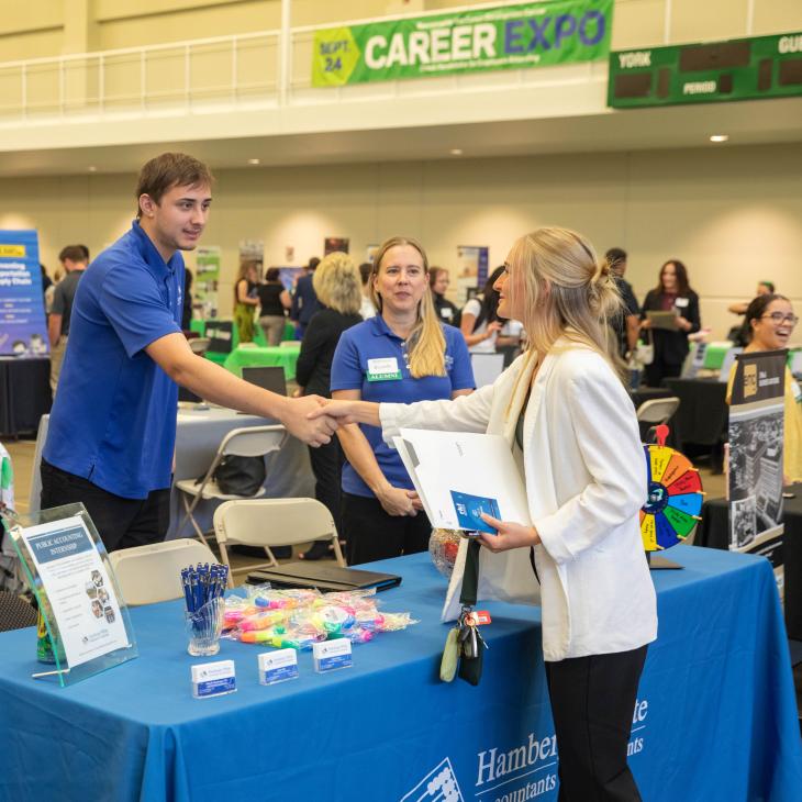 Wide shot of YCP career expo with a student shaking hands with a potential employer