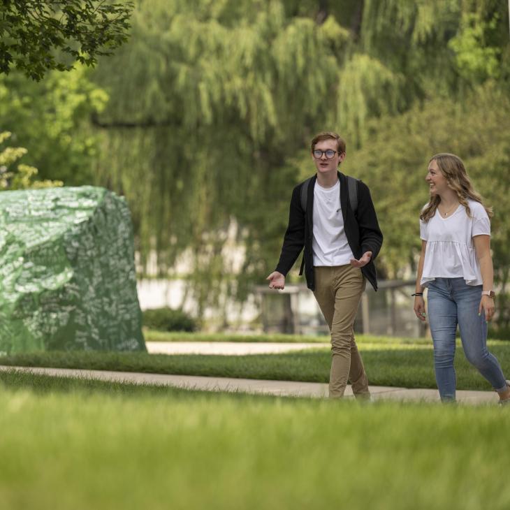 Two students walking past Ol' Spart (the Rock)